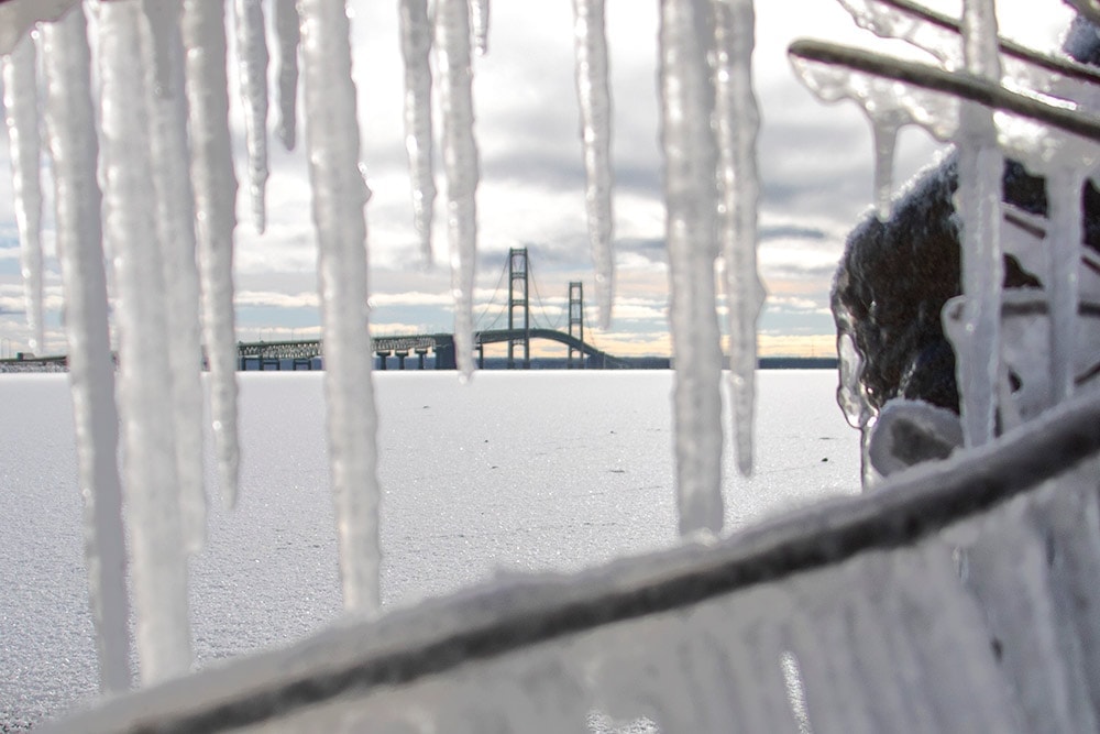A view of Michigan's Mackinac Bridge in the winter. Icicles frame the bridge.
