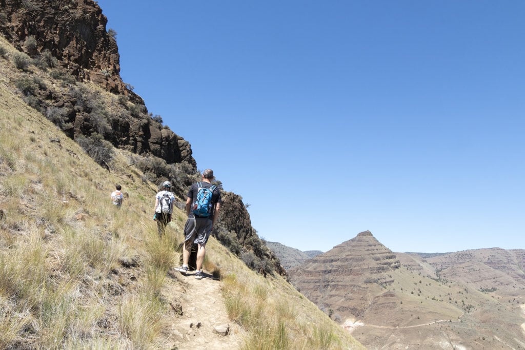 Hiking up to see Blue Basin from above. People high up on a mountain hiking a narrow trail along the edge of the mountain.