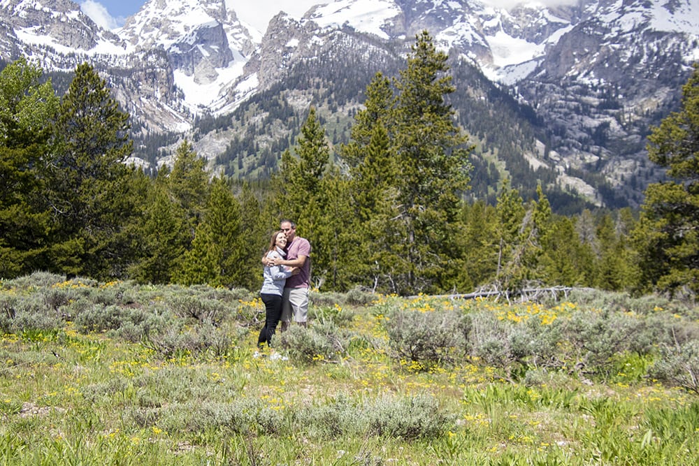 A couple standing in wildflower field in front of the Grand Teton mountains