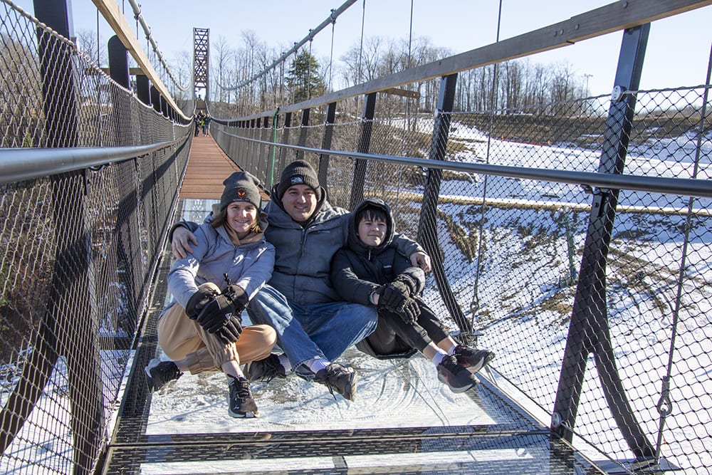 Sitting on the glass panel floor of the longest timber tower skybridge in michigan