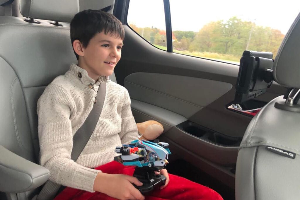 A boy is sitting in a car playing the Nintendo Switch. He is playing the game Starlink.