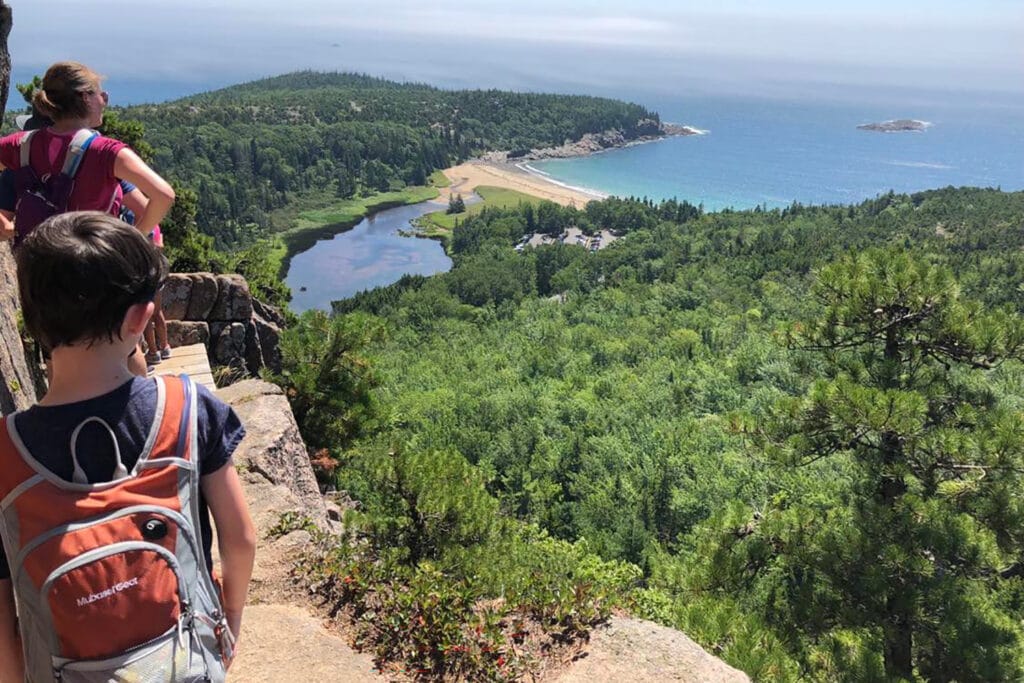 People standing along a skinny cliffside trail in Acadia, one of the best hikes in Acadia National Park.