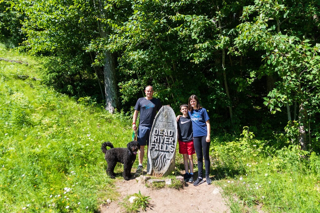 Dead River Falls trail marker. It looks like an old tree trunk that's been shaped into an oval and has dead river falls carved into it.