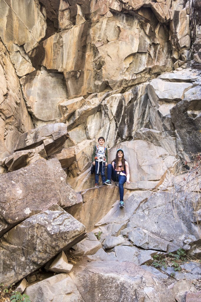Kids resting on the rocky canyon walls hiking to Hanging Lake.
