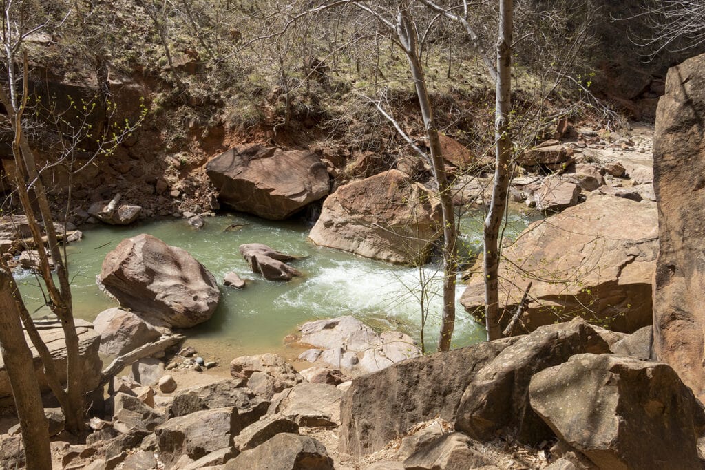 A view of green blue water surrounded by large boulders at Zion National Park.