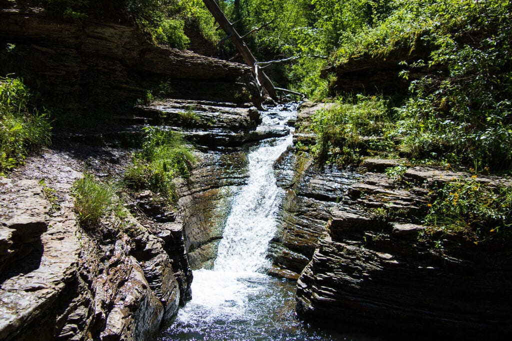 Captivating image of Devil's Bathtub natural waterslide in Spearfish Canyon. Crystal-clear water cascading down smooth rock formations, inviting adventure and exploration.