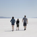 USA destination dupes, Bonneville Salt Flats instead of Badwater Basin. Never ending white salt with mountains in the background. A family is walking across the salt flat.