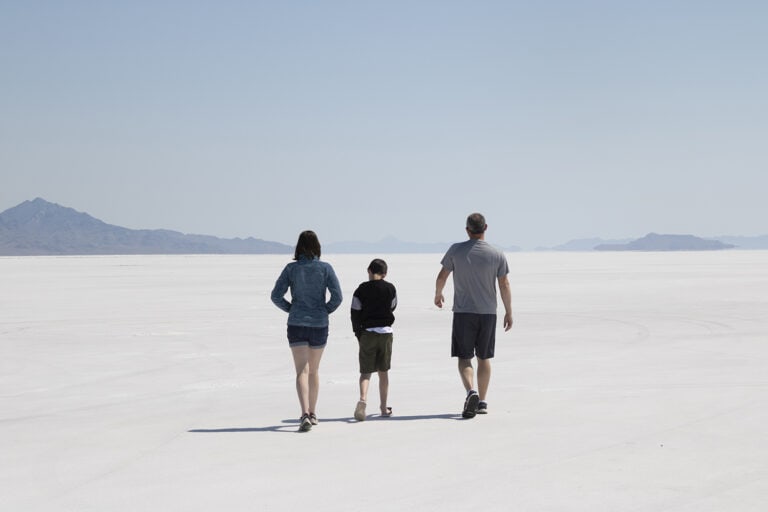 USA destination dupes, Bonneville Salt Flats instead of Badwater Basin. Never ending white salt with mountains in the background. A family is walking across the salt flat.